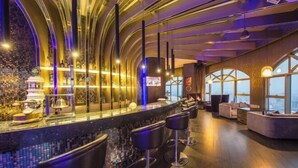 A modern bar area with a curved counter, bar stools, and large windows offering a view. - Joyc Hotel Dongguan (Dongguan)