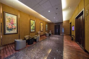 Un couloir d’hôtel avec des œuvres d’art encadrées accrochées aux murs, des coins salon et un comptoir de réception.