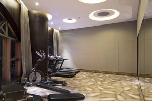 Une salle de sport équipée de tapis de course, de vélos d’appartement et d’un banc de musculation.