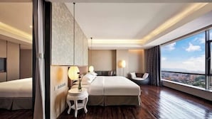 A modern hotel room with a large bed, a bedside table with a lamp, a chair, and a view of the city. - Joyc Hotel Dongguan (Dongguan)