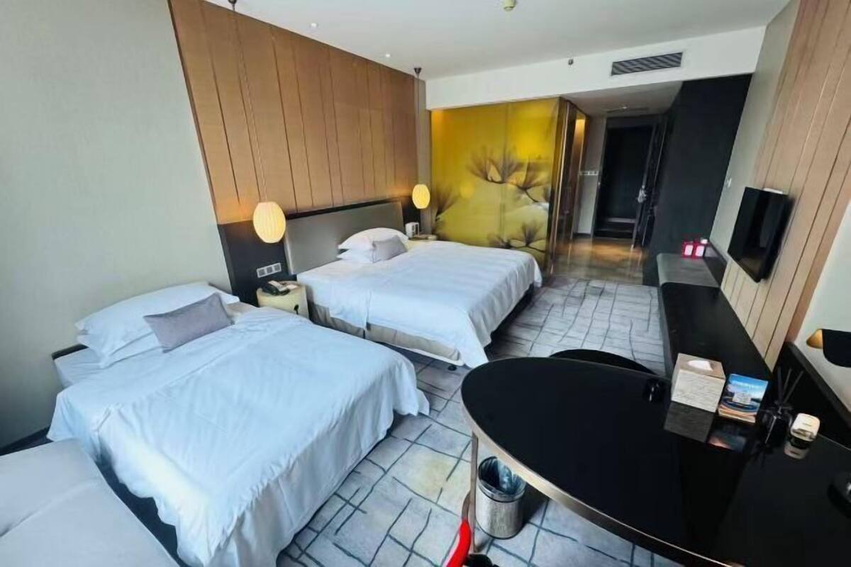 Een hotelkamer met twee bedden, een bureau, een spiegel en een televisie.