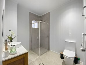 A modern bathroom with a glass shower enclosure, a white sink, and a toilet.