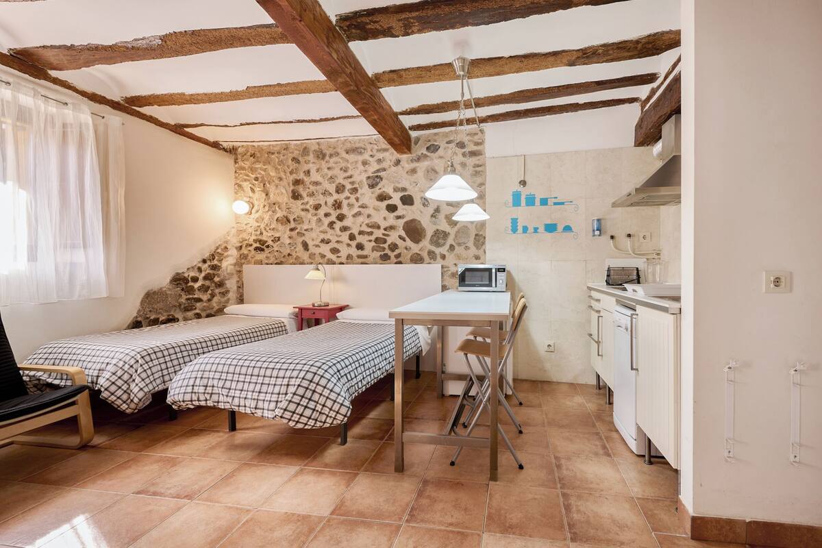 Une petite chambre comprenant un lit, un bureau et une kitchenette.