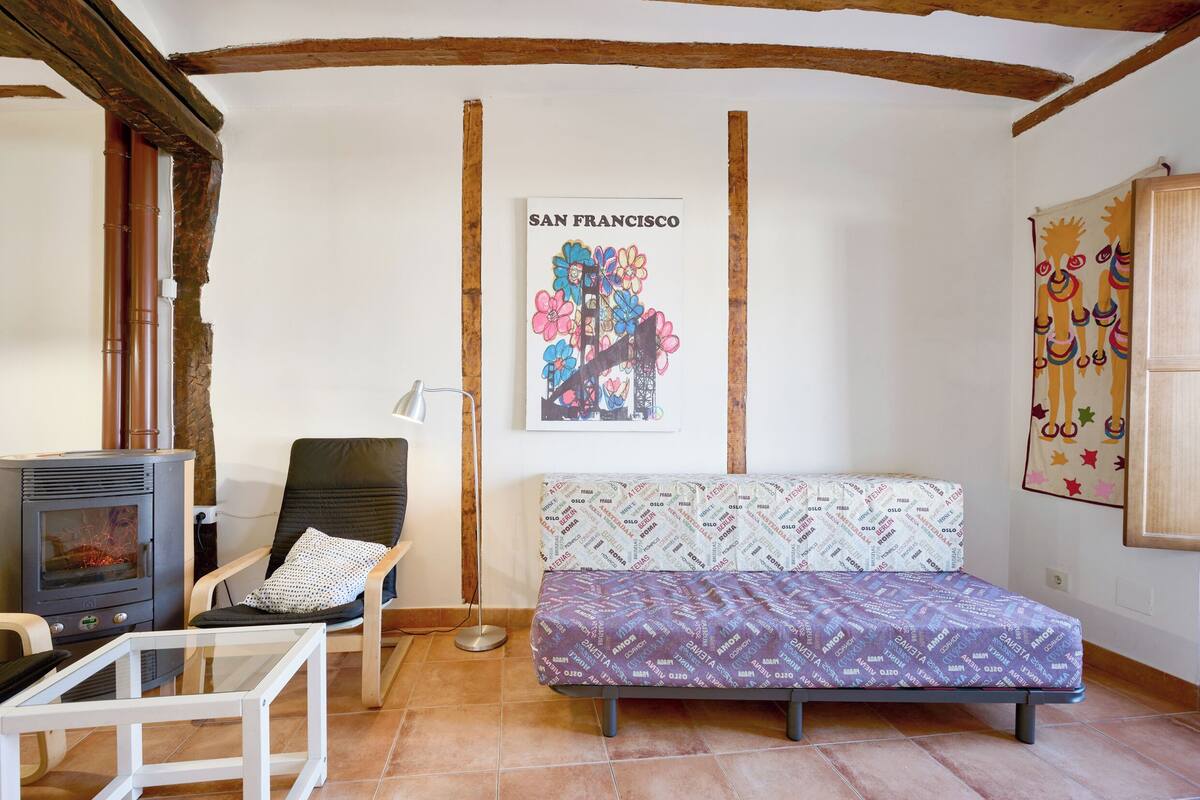 Une pièce confortable avec un canapé, un fauteuil, une petite table et une affiche de San Francisco accrochée au mur.