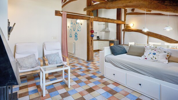A cozy room with a checkered floor, a bed with pillows, a white sofa, and a small table. - San Francisco 58  (Santo Domingo de la Calzada)
