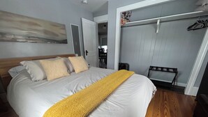 Ein Schlafzimmer mit einem großen Bett, Holzboden, einem Kleiderschrank und einem Bild an der Wand.