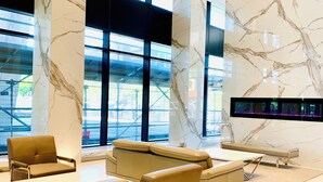Una hall moderna con colonne in marmo, sedute in pelle e un grande schermo digitale.