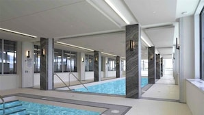 Una piscina interna con acqua limpida, circondata da pareti con un motivo simile al marmo e un pavimento piastrellato.