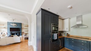 A modern kitchen with dark cabinetry, a built-in oven, and a stainless steel range hood. - NEW: Luxurious 2 bed 2 bath, E14 Flat (Greater London)