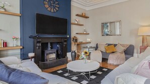 A living room with a fireplace, a large clock, and a television. - NEW: Luxurious 2 bed 2 bath, E14 Flat (Greater London)