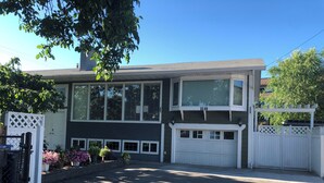 Une maison à deux étages avec un garage, de grandes fenêtres et une clôture blanche.