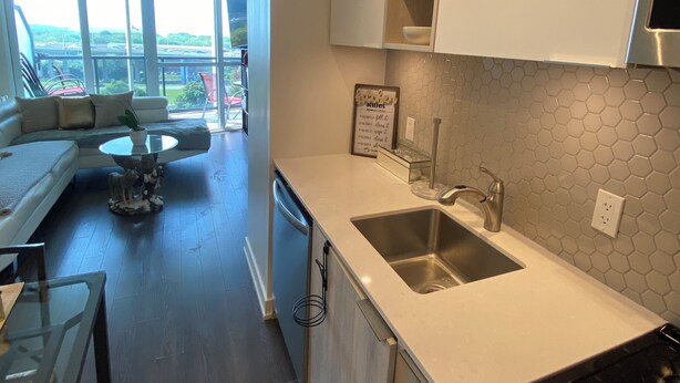 A modern kitchen with a large window, a dining area with a sofa, and a view of the cityscape. - CityView Toronto CN Tower Waterfront (Toronto)