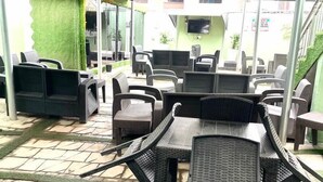 Un espace extérieur aménagé en terrasse, avec des meubles en osier et une partie couverte.
