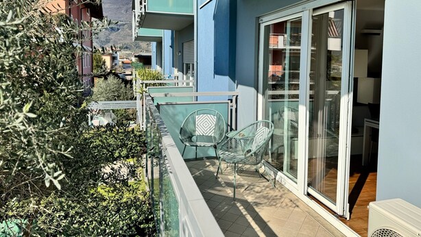A balcony with a glass door, a small table, and two chairs.