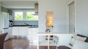 A modern kitchen with white cabinets, a built-in microwave, and a large window.
