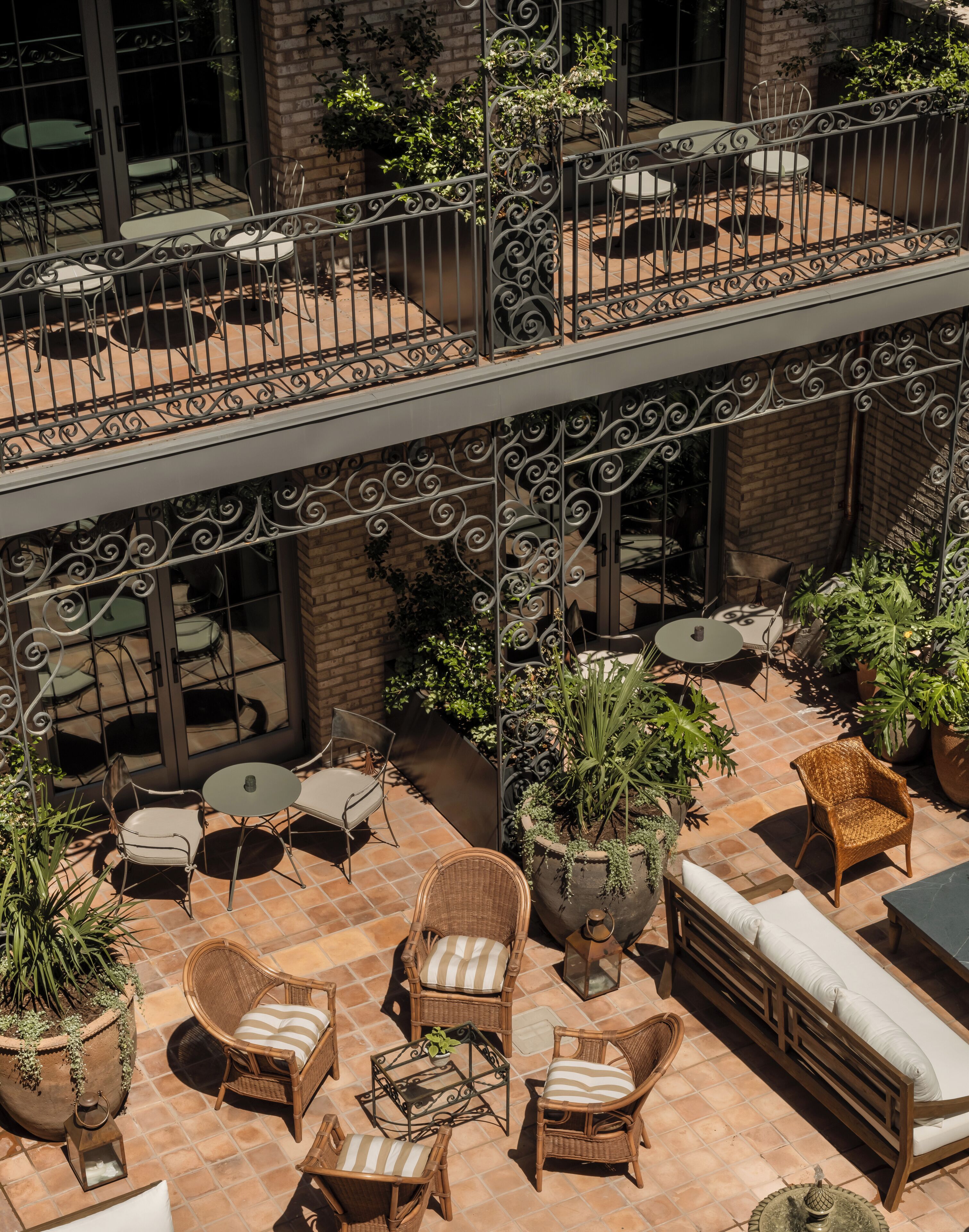A multi-level outdoor patio with wicker furniture, potted plants, and a brick wall.