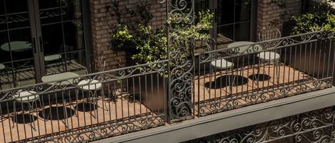 A multi-level outdoor patio with wicker furniture, potted plants, and a brick wall.
