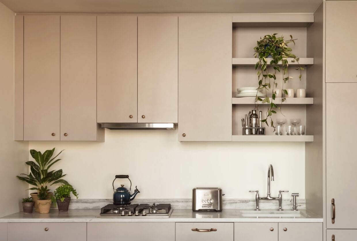 A kitchen with cabinets, a stove, a sink, and potted plants.