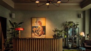 Uma receção com design moderno, ladeada por vasos de plantas e um grande quadro abstrato.