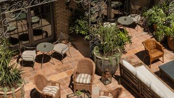 Un patio al aire libre con mobiliario de mimbre, una jardinera grande y un muro de ladrillo.