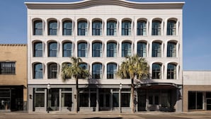 Um edifício de vários andares com fachada simétrica, grandes janelas e telhado plano.