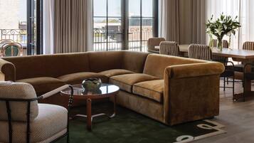 A living room with a sectional sofa, a round coffee table, and a dining area with striped chairs.