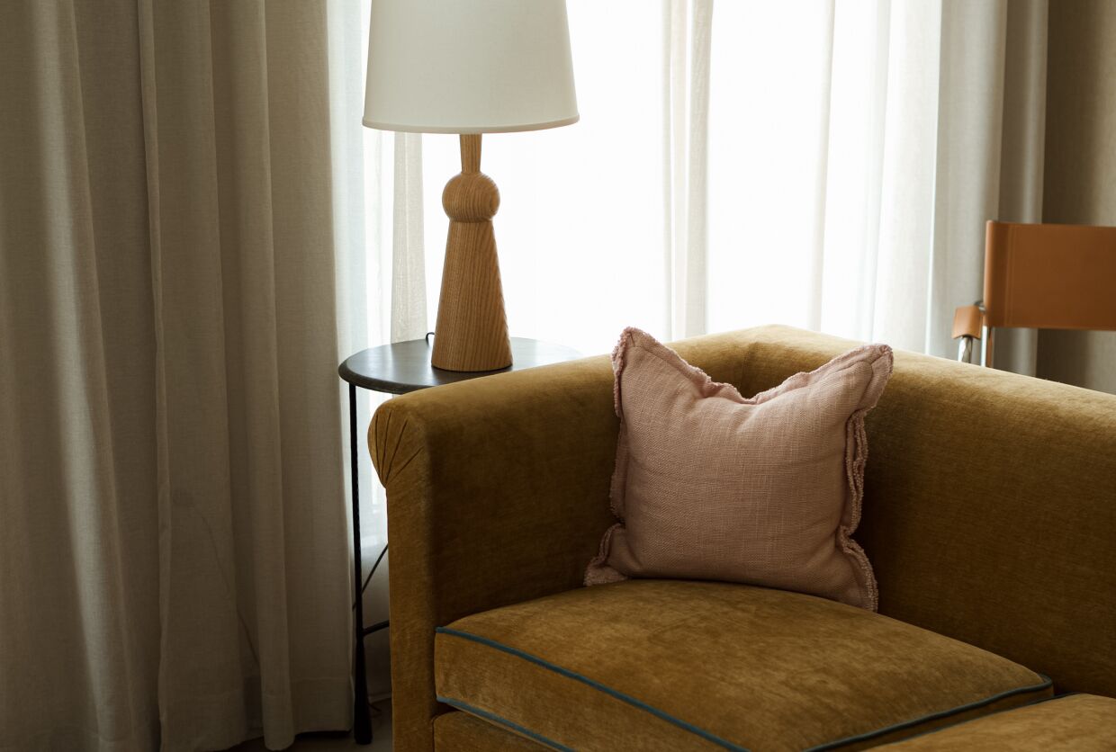 A room with a sofa, a lamp, and a chair.