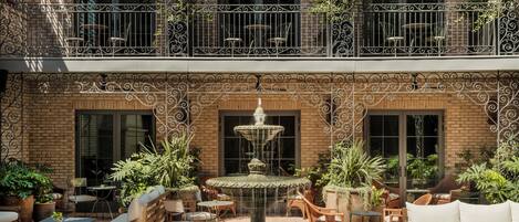 A multi-level outdoor patio with a central fountain, wicker furniture, and potted plants.