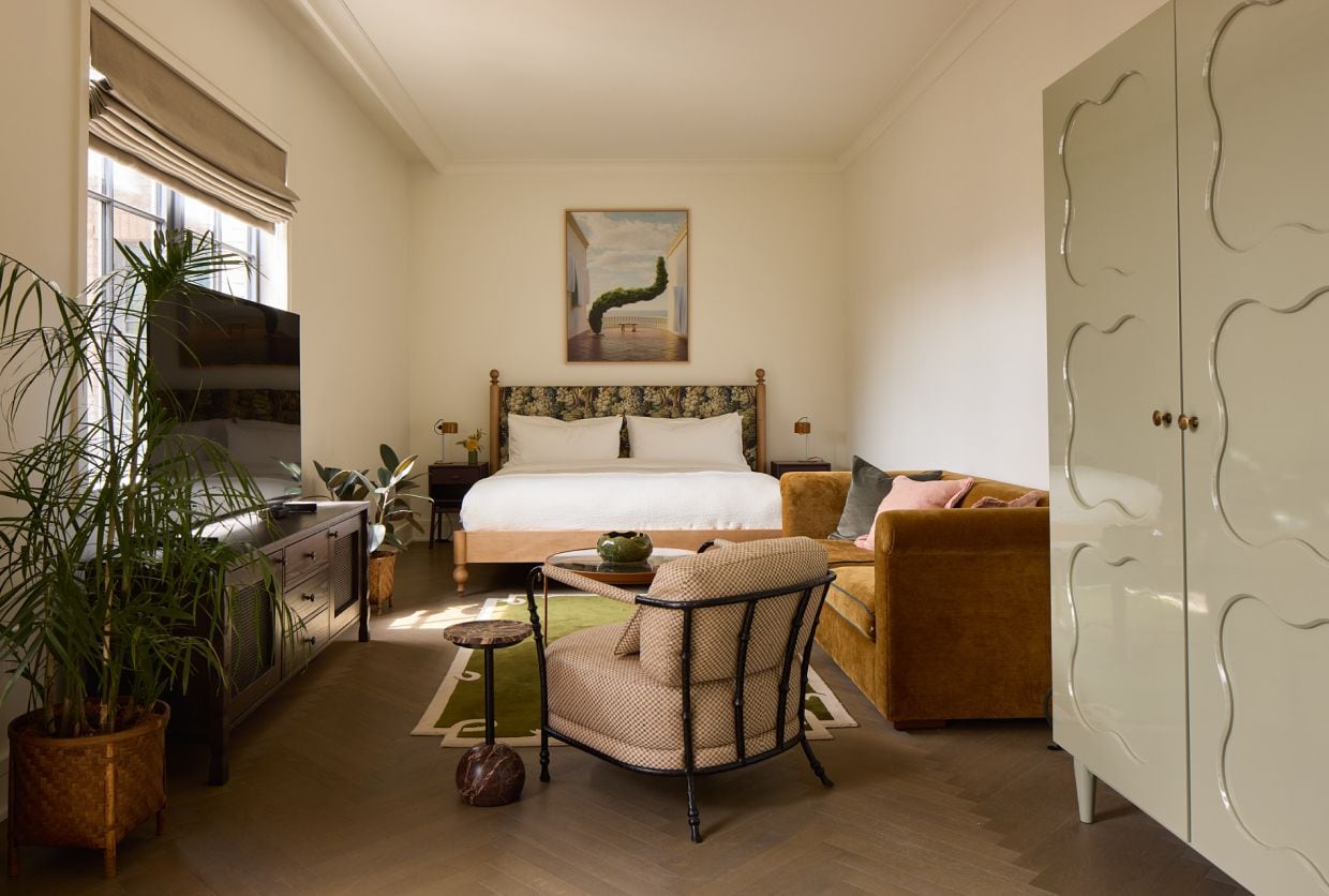 Ein Schlafzimmer mit Bett, Sessel, Sofa, Kleiderschrank und einem Bild an der Wand.