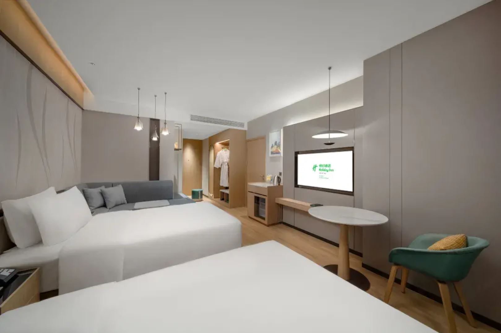 Habitación de hotel con dos camas, un escritorio, una silla, un televisor y un armario.