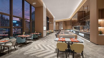 Un restaurante moderno con ventanas amplias, una barra central y diversas opciones de asientos.