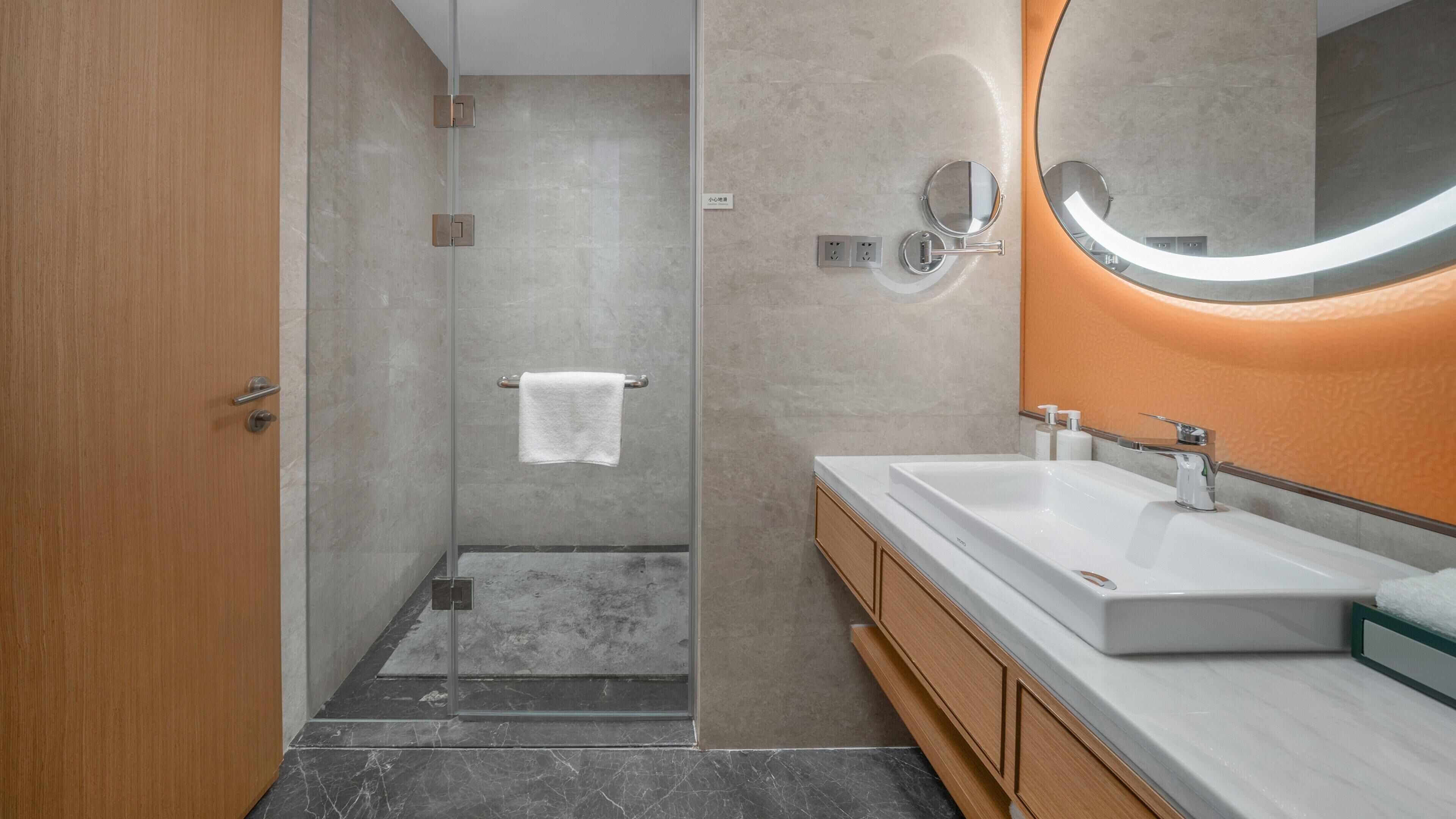 A modern bathroom with a shower, a sink, and a mirror.
