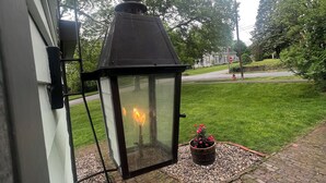 Un farol con llama, una planta en maceta y un sendero de ladrillo.