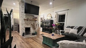 Una sala moderna con chimenea de piedra, un sofá de cuero negro y una mesa de centro verde.