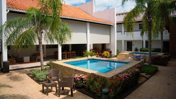 A courtyard with a swimming pool, palm trees, and outdoor seating. - Palma Dorada (Tucacas)