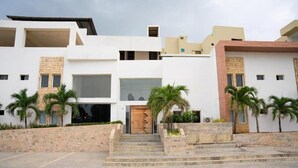 A modern building with a central entrance, multiple balconies, and palm trees. - Palma Dorada (Tucacas)