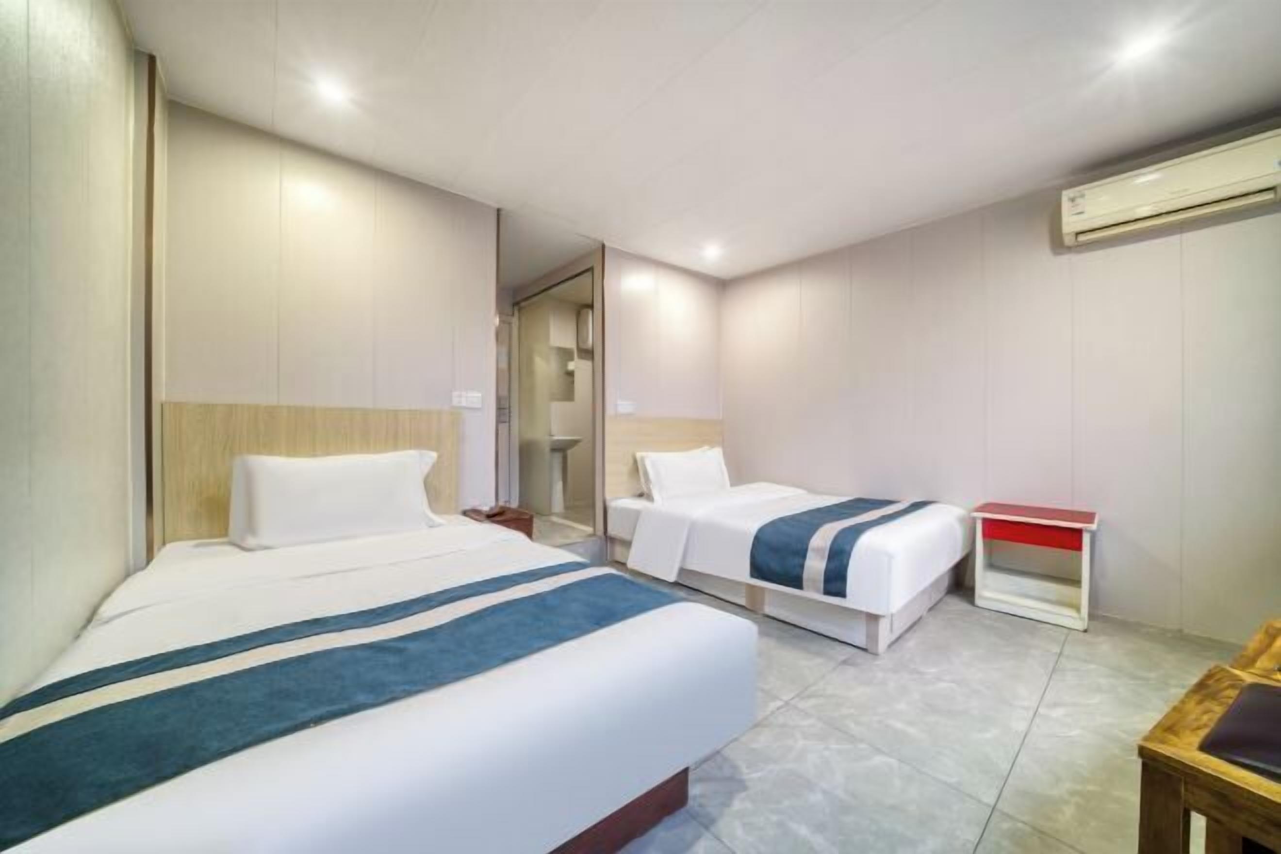 Une chambre d’hôtel avec deux lits, une petite table et un appareil de climatisation.