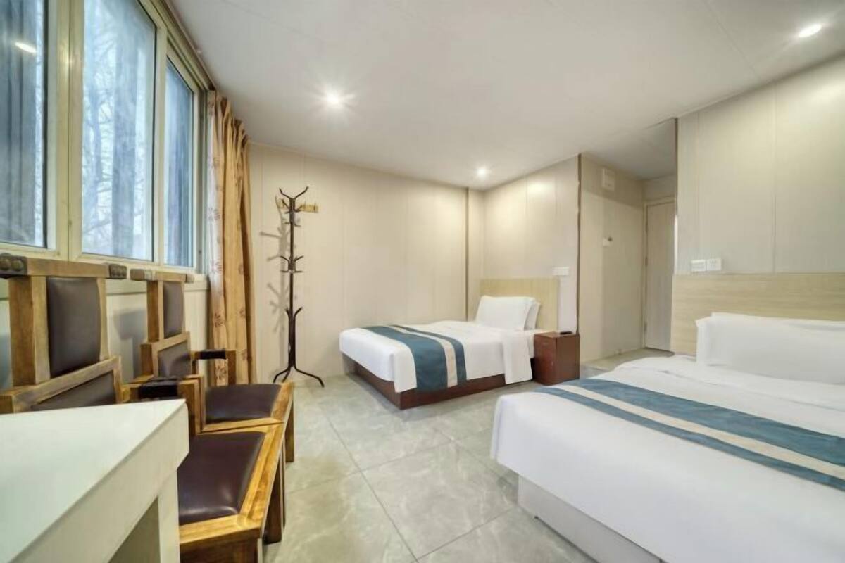 A hotel room with two beds, a desk, and a chair.