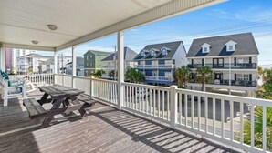 A covered porch with picnic tables, overlooking a row of colorful houses with balconies.