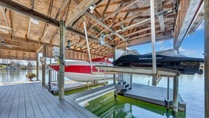 A covered dock with boats, wooden deck, and a calm water body. - Lakefront Property! Gentle slope to the water, firepit, water skis, paddleboards (Moneta)