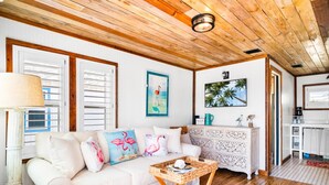 A cozy living room with a white sofa, wooden ceiling, and a decorative wall hanging. - Prime Location in the Heart of Port A – Steps Away from Restaurants, Shops, Parks, and the Beach! (Port Aransas)