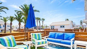 A deck with outdoor furniture, including a sofa and chairs, and a blue umbrella. - Prime Location in the Heart of Port A – Steps Away from Restaurants, Shops, Parks, and the Beach! (Port Aransas)