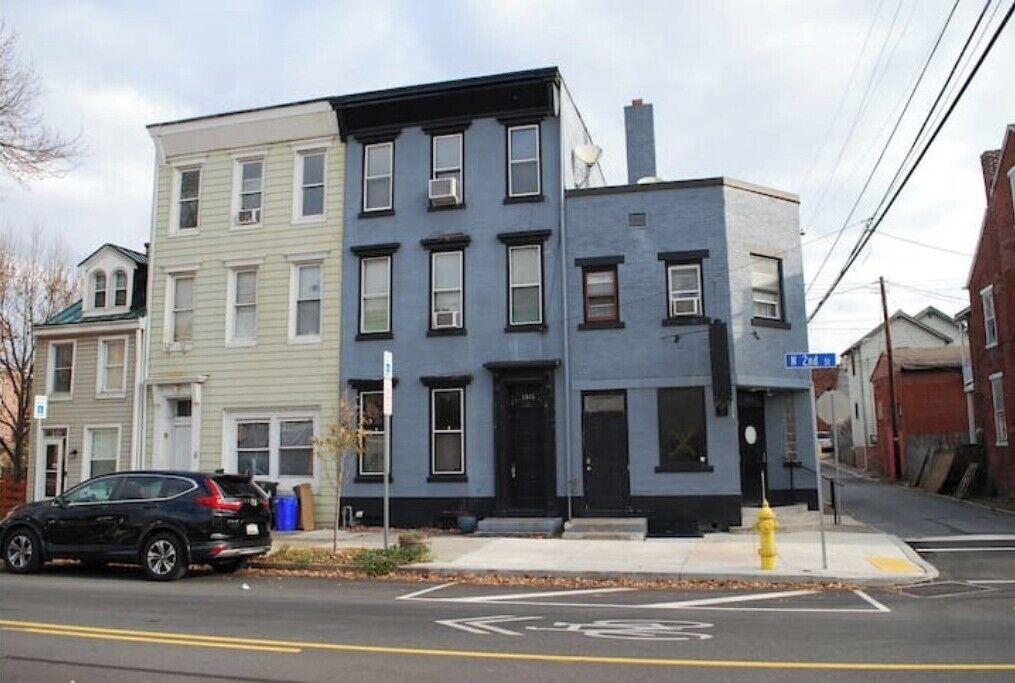 A multi-story building with a mix of residential and commercial spaces, a fire hydrant, and a street sign.