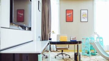 Habitación de hotel con escritorio, silla y zona de juegos infantil que incluye un tobogán.