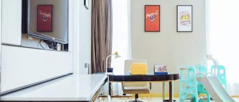 A hotel room with a desk, chair, and a children's play area including a slide.