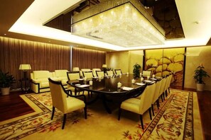 A conference room with a large round table, multiple chairs, and a chandelier. - Metropark Hotel Yancheng (Yancheng)