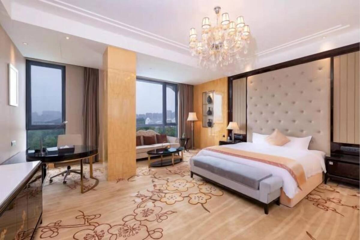 A hotel room with a large bed, a desk, and a view of the city.