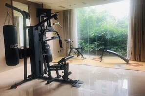 Uma academia com saco de pancada, aparelhos de musculação e bicicleta ergométrica.