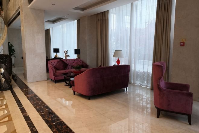 Un vestíbulo amplio con un sofá rojo, una silla y una mesa de centro.