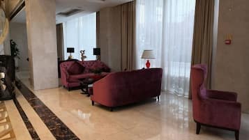 Un vestíbulo amplio con un sofá rojo, una silla y una mesa de centro.